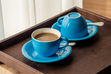 Close-up view of the blue coffee mug, clear glass for drinking water, placed on a tray to bring clear drinks, seen at resorts, hotels or bakeries