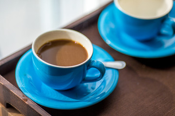 Close-up view of the blue coffee mug, clear glass for drinking water, placed on a tray to bring clear drinks, seen at resorts, hotels or bakeries