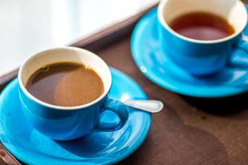 Close-up view of the blue coffee mug, clear glass for drinking water, placed on a tray to bring clear drinks, seen at resorts, hotels or bakeries