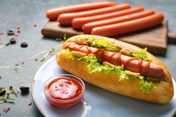 Plate with tasty hot dog on table