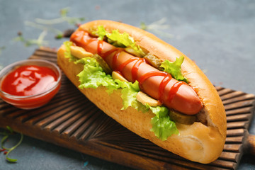 Tasty hot dog and sauce on table