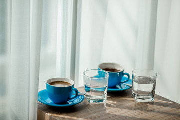 Close-up view of the blue coffee mug, clear glass for drinking water, placed on a tray to bring clear drinks, seen at resorts, hotels or bakeries