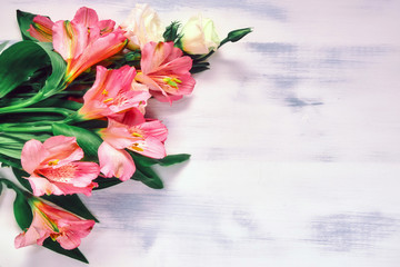 Bouquet of pink inca lilies on a white wooden background
