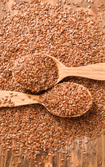 Spoons with flax seeds on wooden background