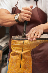 Close-up of skilled shoemaker's hands cutting shoe sole