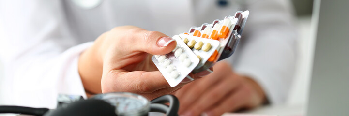 Female doctor hand holding pack of different tablet