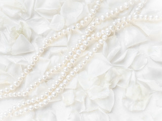 Fototapeta na wymiar Pearl necklace on a background of white rose petals. Ideal for greeting cards for wedding, birthday, Valentine's Day, Mother's Day