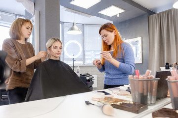 Fototapeta premium A young woman works as a model in a master class for makeup artists. Photo through a mirror. Learning new skills, raising the level of professionalism, training. Style training, beauty industry