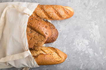 Reusable grocery bag with fresh baked bread on a gray concrete background. top view, copy space.