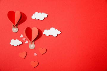 top view of paper heart shaped air balloons in clouds on red background
