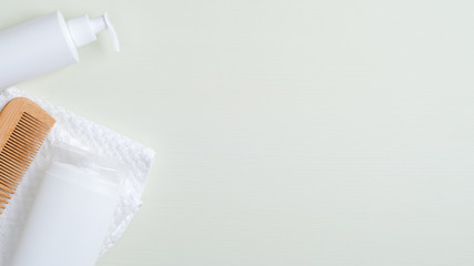 Top view shampoo bottle, hair lotion, bamboo hair comb and bath towel. Natural cosmetic products, hair care and SPA treatment concept. Banner mockup for beauty salon