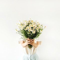 Young pretty woman hold in hands bouquet of white chamomile daisy flowers on white background.