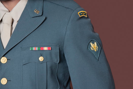 Close-up of US military officer's uniform with badge over brown background