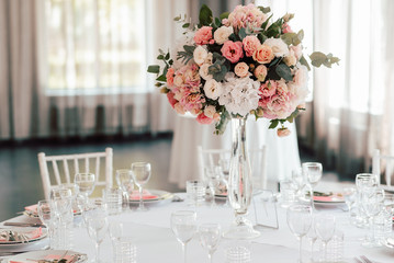 Floral arrangement of various soft pink and white flowers in the center of the festive table in a restaurant