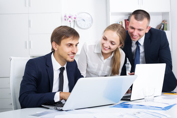 Three cheerful coworkers different sexes working in company office