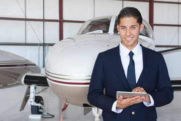 Portrait of handsome young pilot using tablet PC in front of airplane © MDBPIXS
