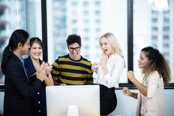 Coworkers looking at a computer and discussing over new business plan. Business team working together on computer in office.