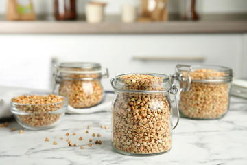 Uncooked green buckwheat grains on white marble table