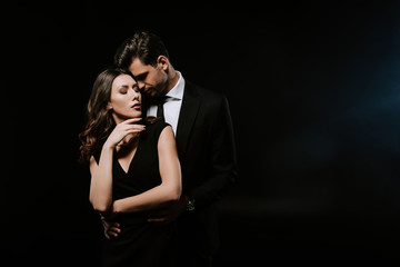 sensual man standing with attractive woman in dress on black