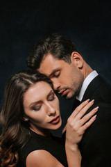 young woman hugging handsome man isolated on black