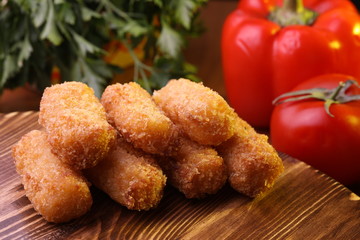 Cheese sticks on a wooden surface next to the greens.