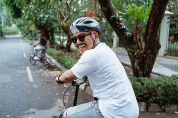 Asian youths look back and smiling when riding bicycles on the road in a park environment