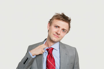 Portrait of young businessman loosening tie over colored background
