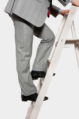 Low section view of a businessman climbing up a ladder