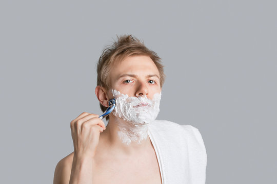 Portrait Of Young Man Saving With Towel On Shoulder Over Colored Background