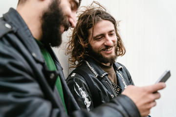 Photo of bearded joyful men bikers using cellphone and smiling