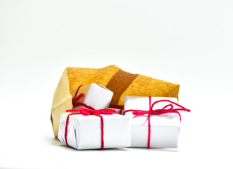Small white gift box tied with a red string placed in a brown paper bag on a white background - Powered by Adobe