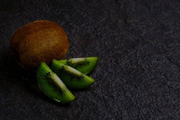 Sliced kiwi at stone background low key copy space