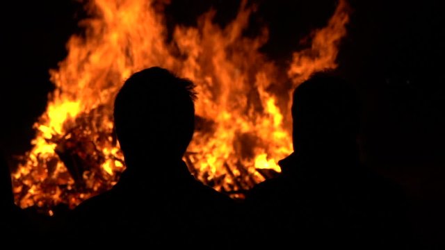 Fire at night with human silhouettes