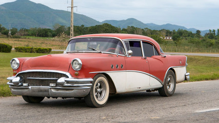 Fototapeta na wymiar red cuban classic car driving on a road, cuba
