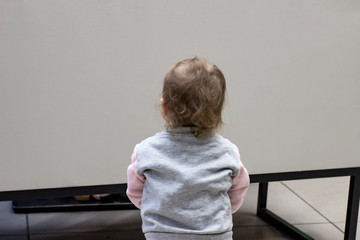 The child looks at a white board, visas from behind. Back view of a little girl looking at a light...