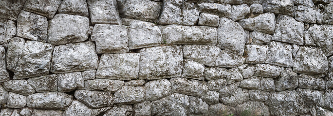 Old stone wall - ancient masonry with a hewn texture of a stonewall background.