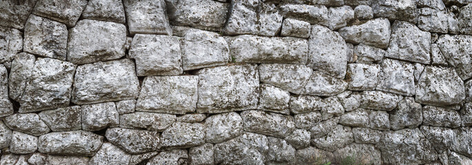 Old stone wall - ancient masonry with a hewn texture of a stonewall background.