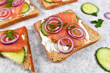 Slice of healthy wholegrain toast bread topped with smoked salmon fish, red onions and spring onions and cucumber on horseradish 