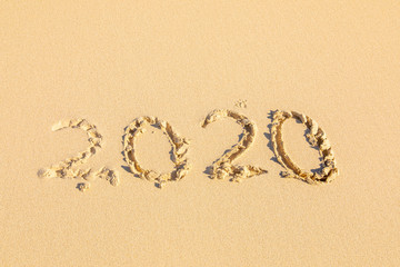 Summer beach holiday 2020 season golden sand - old year - decade - new season lettering on the beach - Numbers 2020 year on the sea shore, message handwritten New Years concept copy empty space
