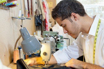 Side view of young man tailoring cloth in shop