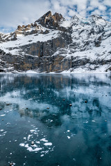 Fototapeta na wymiar frozen Lake Oeschinensee with reflection of the Blümlisalp Mountains in the Swiss Alps