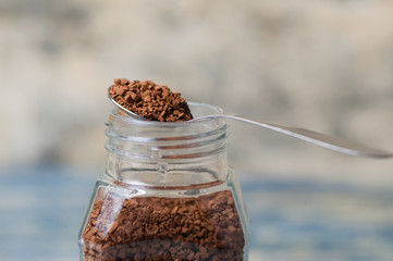 Spoon with instant coffee over the can closeup. Coffee granules macro.