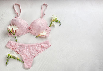 Sexy women's underwear and flowers on light background, flat lay. Space for text