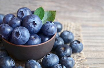 Freshly picked organic blueberries in a brown bowl on wooden background.Blueberry. Bilberries. Healthy eating,vegan food or diet concept with copy space.Selective focus.