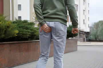 Man suffering from hemorrhoid pain outdoors, closeup