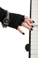 Close-up of female hands with fingerless gloves and bracelet playing piano keyboard