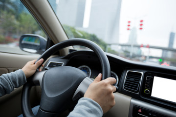 Naklejka premium People hands holding steering wheel while driving car on city road