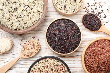 Different sorts of rice on white wooden table, flat lay