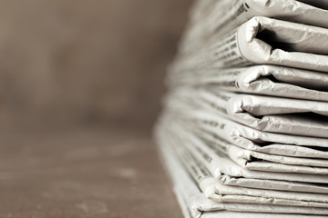 Stack of newspapers on table, closeup with space for text. Journalist's work