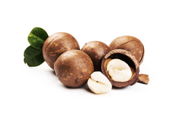 Macadamia nut with pieces and green leaves isolated on a white background